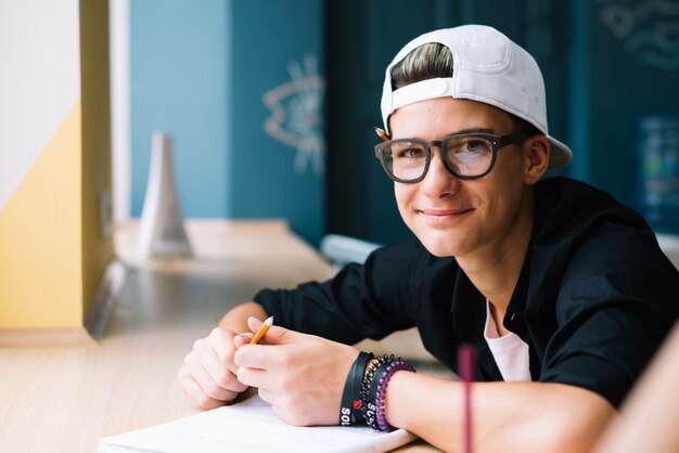 Content stylish student posing at table