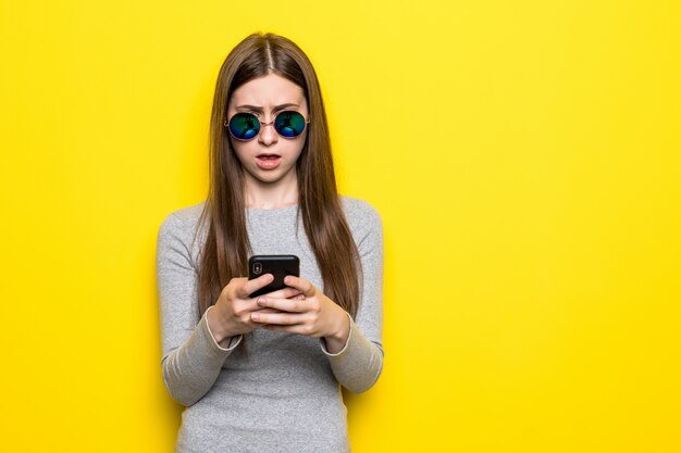 Контент подростка с длинными волосами, держит современный сотовый телефон, пролистывает социальные сети