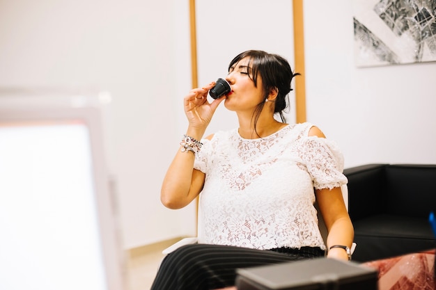 Foto gratuita donna di contenuto che gode del caffè in ufficio