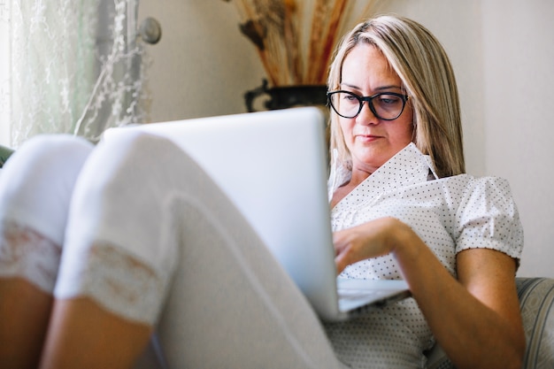 Content woman relaxing with laptop at home