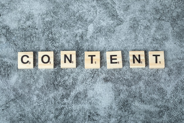 Content writing with black letters on wooden dices on blue background. High quality photo