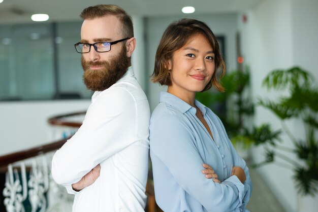 Content young multi-ethnic colleagues standing back to back