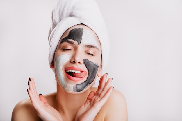 Contented lady licks her lips during sleep procedures for face. Model makes morning routine on isolated wall.