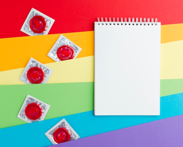 Foto gratuita disposizione del metodo di contraccezione su sfondo arcobaleno con blocco note vuoto