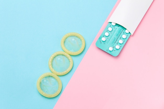 Contraceptive pills and condoms on colored background. view from above. concept of birth control