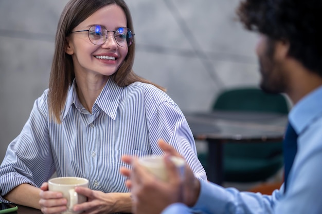 Conversation. Cute young woman in eyeglasses talking to her colleagues