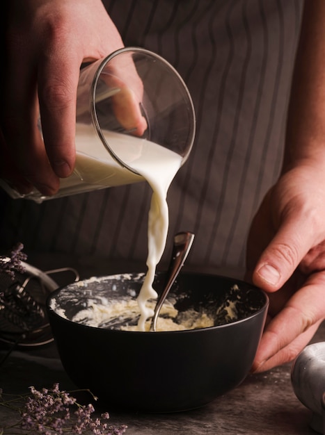 Free photo cook adding milk to bowl mixture