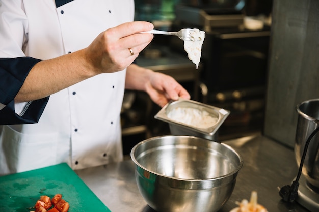 Cook adding sauce from container in bowl 