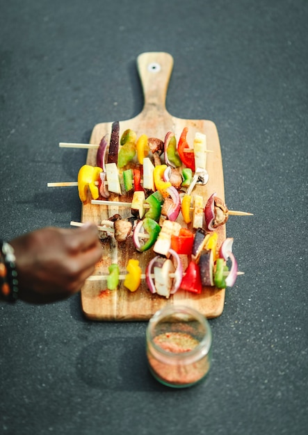 Free photo cook adding seasoning to vegan barbecue skewers