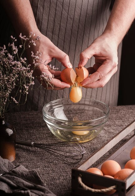 Free photo cook breaking eggs in bowl