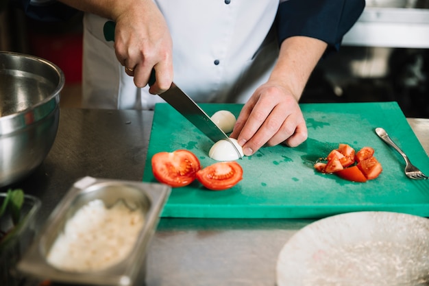 Cook cutting boiled egg on board