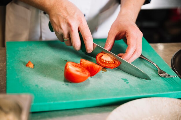 Cook cutting red tomato on board