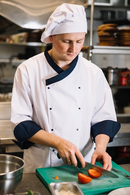 Cook cutting tomato on board 