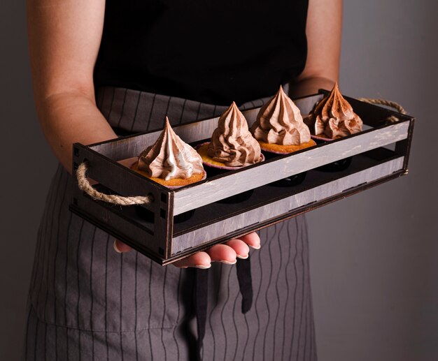 Cook holding tray with cupcakes and icing