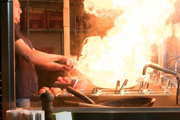 Foto gratuita cuocere è friggere le verdure con le spezie e la salsa in un wok su una fiamma. processo di cottura in un ristorante asiatico.