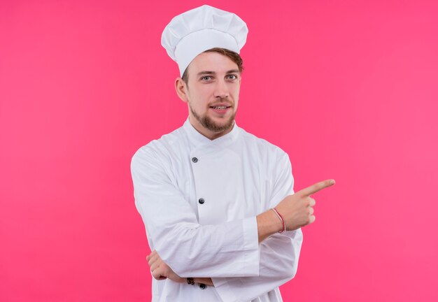 Cook looking at camera pleasure on face pointing away standing over pink wall