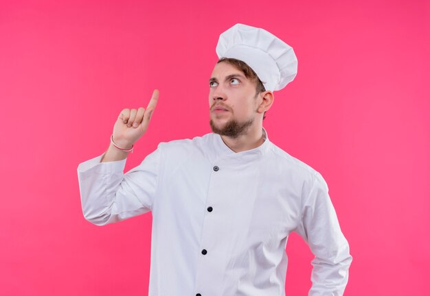 ピンクの壁の上に立って上向きに見上げる料理人