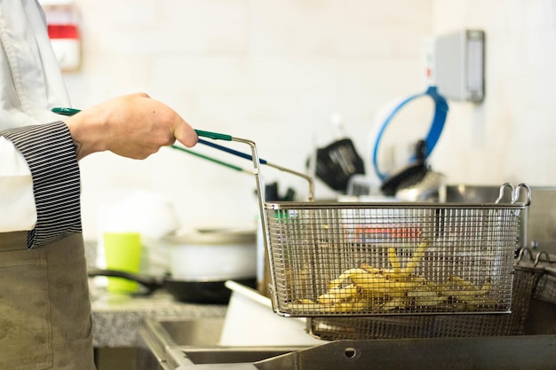 Cook preparing french fries in the kitchen