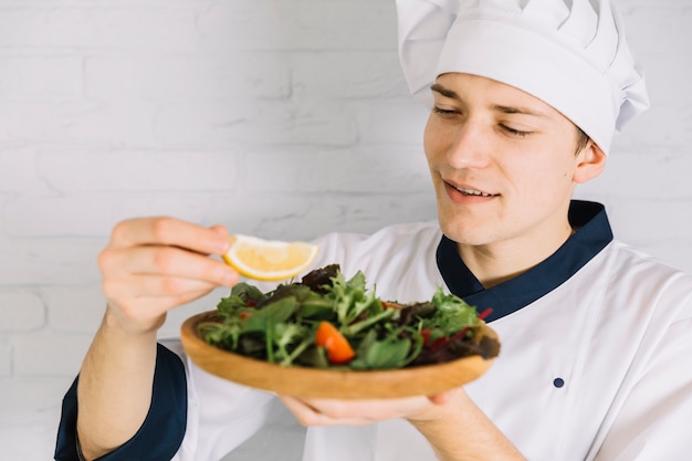 Cook putting lemon on plate with salad 