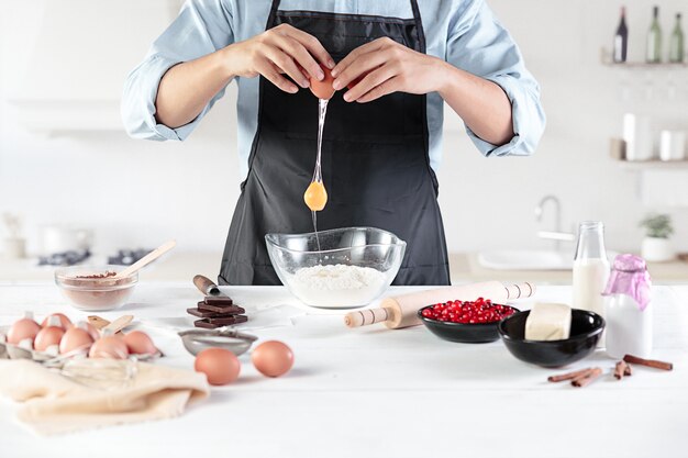 A cook with eggs on a rustic kitchen against the background of men's hands