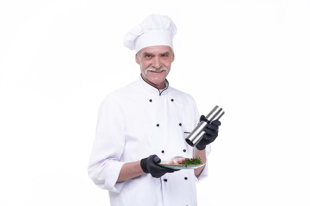 Cook with happy face, elderly chef male holds steak meat and pepper