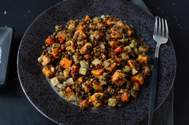 Cooked black lentil with pumpkin served on plate. Closeup