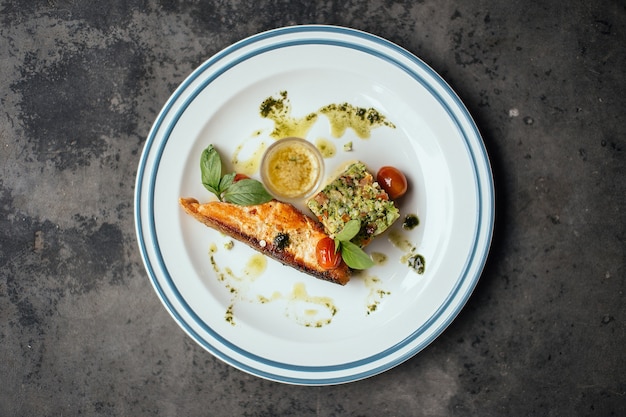 A cooked fish with sauce on tomatoes on a white plate 