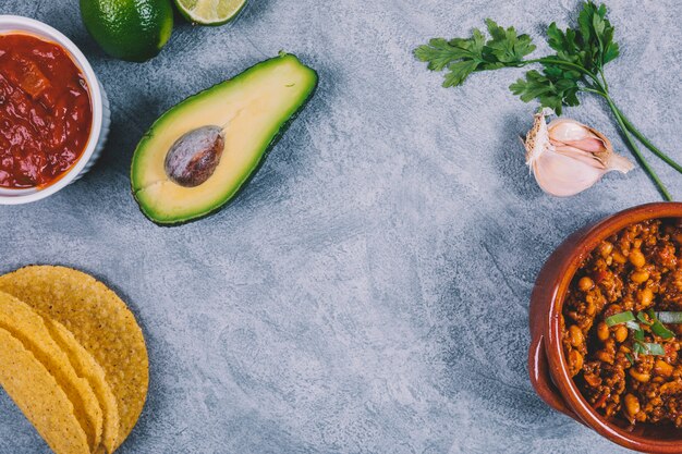 Cooked ground beef; halved avocado; coriander and garlic on concrete background