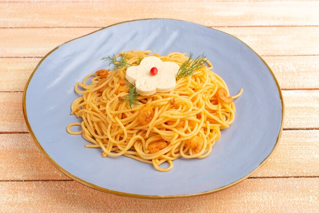 cooked italian pasta tasty meal with greens inside blue plate on cream wood