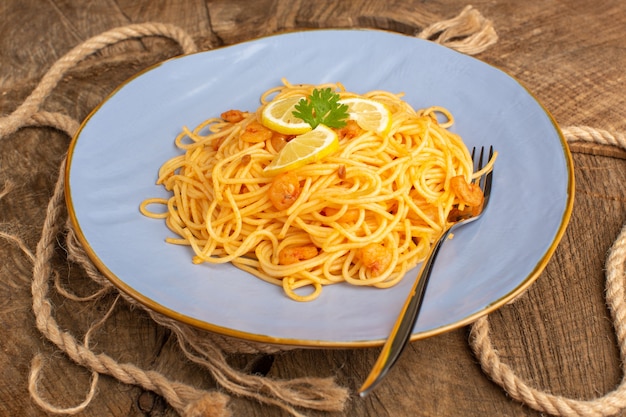 cooked italian pasta with greens inside blue plate with ropes on wood