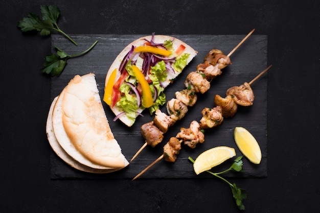 Cooked meat and veggies kebab on black background