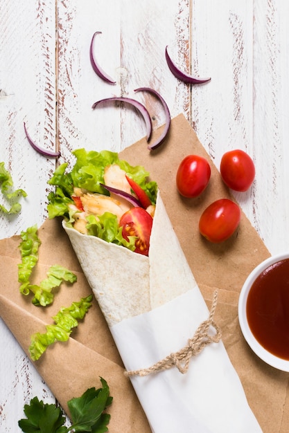 Foto gratuita kebab di carne e verdure cotte avvolto in carta