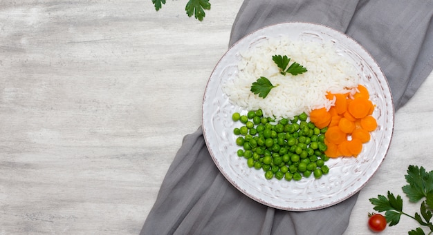 Cooked rice with vegetables and parsley on plate on grey cloth 