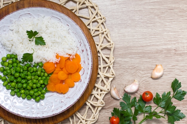 Cooked rice with vegetables and parsley on plate on wooden table