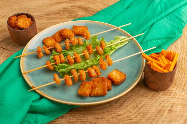cooked shrimps on sticks inside blue plate with green salad on wood
