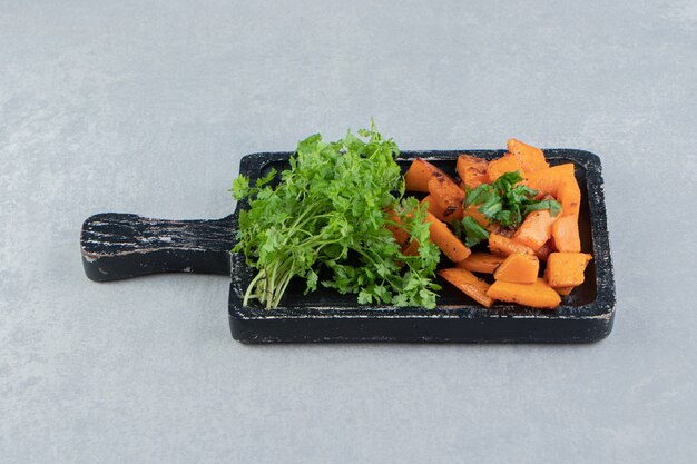 Cooked sliced pumpkin next to parsley, on the tray , on the marble background.