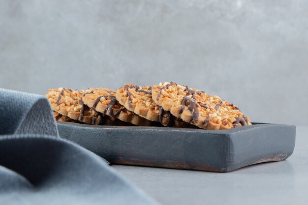 Cookie bundle on a wooden board next to tablecloth on marble background.