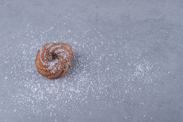 A cookie on a pile of vanille powder on marble surface