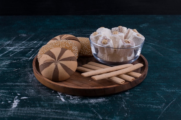 Cookie plate with buns, lokum in a glass cup and waffle sticks in the center