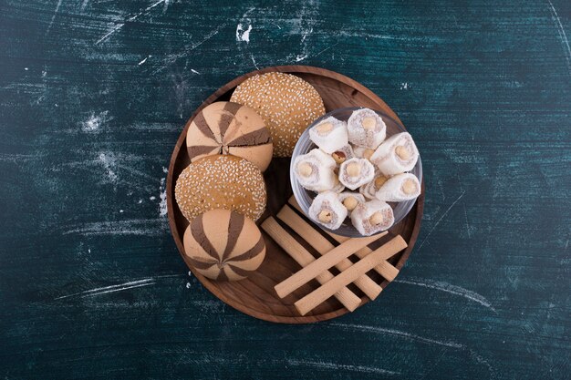 Cookie plate with buns, lokum in a glass cup and waffle sticks in the center