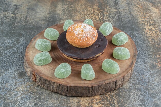 Cookie with chocolate and marmalade candies on wooden piece