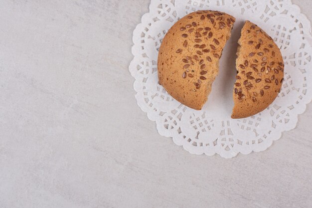 Cookie with sesame seeds on white surface.