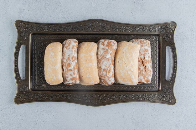Упаковки печенья на богато украшенном подносе на мраморном фоне.