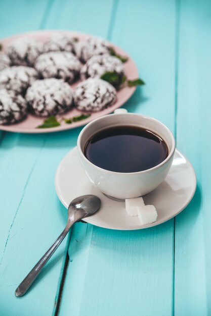 一杯のコーヒーとプレートの青い木製のテーブルの上のクッキー