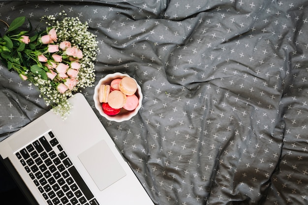 Foto gratuita biscotti e bouquet vicino al computer portatile