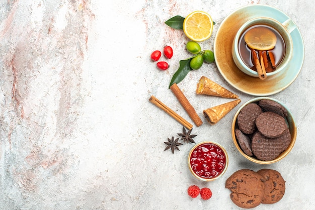 Biscotti ciotola di marmellata biscotti al cioccolato una tazza di tè con bastoncini di cannella al limone