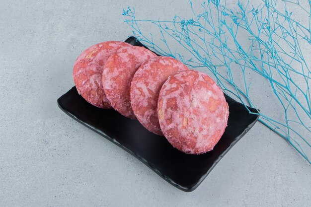 Cookies bundled on a black platter on marble background.