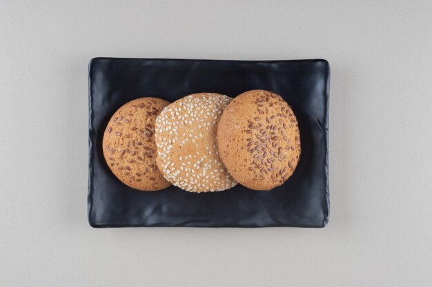 Cookies bundled on a black platter on marble background.