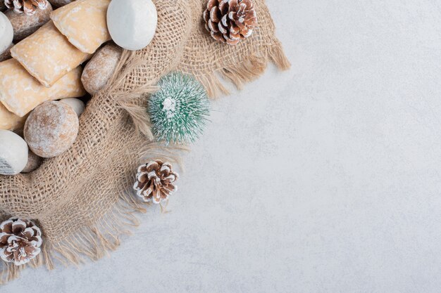 Cookies bundled on a piece of cloth amid christmas decorations on marble surface