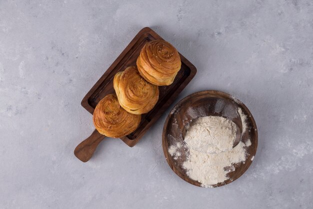 Cookies or buns with flour on a wooden platter , top view